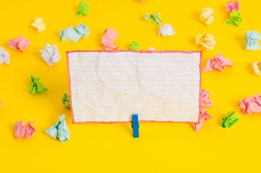 Sarı arkaplandaki boş dikdörtgen kare şekilli hatırlatma notunun etrafına yerleştirilmiş renkli buruşuk çarşaflar. Ofis malzemeleri, boş kağıtlar..