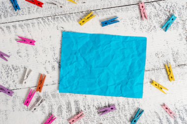 Beyaz ahşap arka planda dikdörtgen kare şeklinde renkli kağıt etrafında renkli clothespin. Boş bir alana anımsatıcı notu. Ofis fikir kağıtları ile hafif ahşap masa.