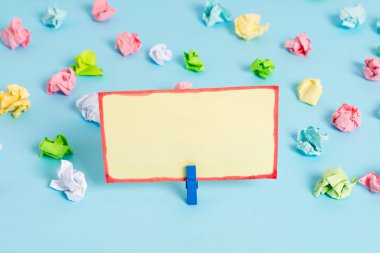 Mavi arka planda boş dikdörtgen kare şeklinde hatırlatma notu etrafında yerleştirilen renkli buruşuk levhalar. Ofis malzemeleri, bir bağlantı elemanı tarafından sabitlenmiş boş kağıt.
