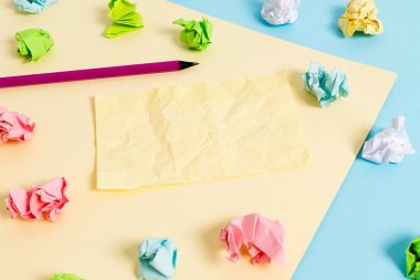 Renkli buruşuk levhalar ve boş dikdörtgen şekilli hatırlatma notu mavi bir arka plan ve sarı kare ortasında yerleştirilir. Ofis malzemeleri, bağlantı elemanı.