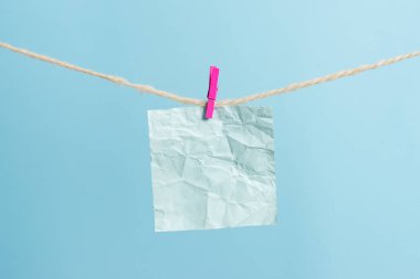 Dikdörtgen şeklinde not renkli kağıt beyaz ahşap arka planda clothespin tarafından bir çamaşır ipi kırpılmış. Kare boş hatırlatma ve ofis ekipmanları malzemeleri hafif ahşap bir masada.