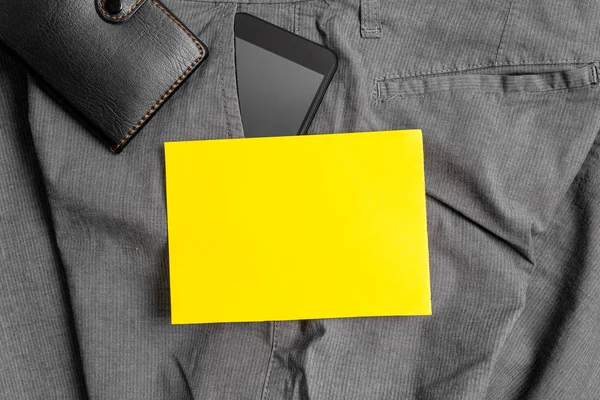 Smartphone device in the trousers front pocket with a wallet and yellow note paper. Modern gadget is placed inside man pants near notation sheet plus purse — Stock Photo, Image