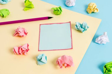 Renkli buruşuk levhalar ve boş dikdörtgen şekilli hatırlatma notu mavi bir arka plan ve sarı kare ortasında yerleştirilir. Ofis malzemeleri, bağlantı elemanı.