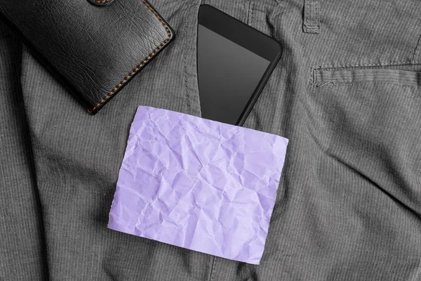 Smartphone-enhet i byxorna framficka med plånbok och lila anteckningspapper. Modern gadget är placerad inuti man Pants nära notation Sheet plus handväska — Stockfoto