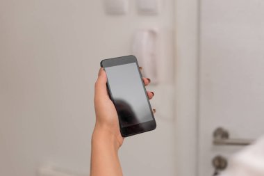 Genç bayan evin içinde karanlık bir akıllı telefon kullanıyor. Evin ambiyansında siyah bir cep telefonu tutan kadın. Boş alan ile teknolojik cihazlar ve ofis malzemeleri ile Kız.