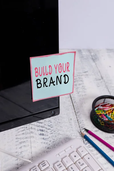 단어 쓰기 텍스트 는 브랜드를 구축 할 수 있습니다. 광고 캠페인을 사용하여 브랜드 자산을 강화하기위한 비즈니스 개념 키보드 및 고정 근처 검은 색 컴퓨터 화면에 테이프 종이 를 참고. — 스톡 사진