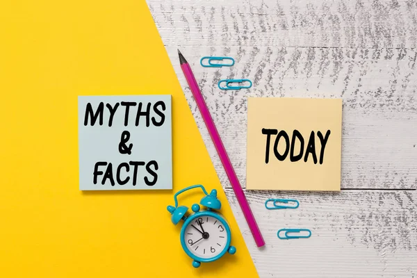 Tulisan kata Myths And Facts. Konsep bisnis untuk cerita tradisional tentang peristiwa bersejarah yang seolah-olah penanda Notepads pena kertas berwarna alarm jam latar belakang kayu . — Stok Foto