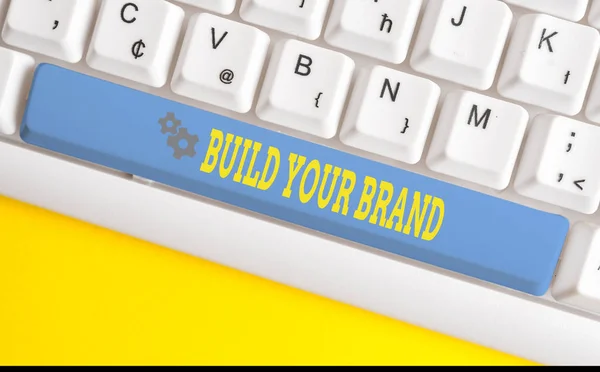 Text sign showing Build Your Brand. Conceptual photo enhancing brand equity using advertising campaigns White pc keyboard with empty note paper above white background key copy space.