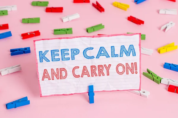 Text sign showing Keep Calm And Carry On. Conceptual photo slogan calling for persistence face of challenge Colored clothespin papers empty reminder pink floor background office pin.