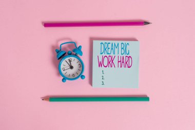El yazısı metin Dream Big Work Hard. Kavram anlamı Kendinize inanın ve hayalleri ve hedefleri metal vintage çalar saat uyandırma boş not defteri işaretleri renkli arka plan izleyin.