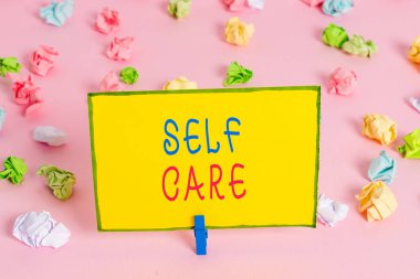 Kelime yazma metni Self Care. Bir geliştirmek için harekete geçme uygulaması için İş konsepti kendi sağlık Renkli buruşuk kağıtları boş hatırlatma pembe zemin arka plan clothespin olduğunu.