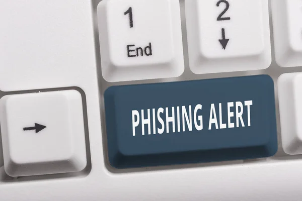 Schreiben Notiz zeigt Phishing-Alarm. Geschäftsfoto, das bewusst betrügerische Versuche zeigt, an sensible Informationen zu gelangen weiße PC-Tastatur mit Notizpapier über weißem Hintergrund. — Stockfoto