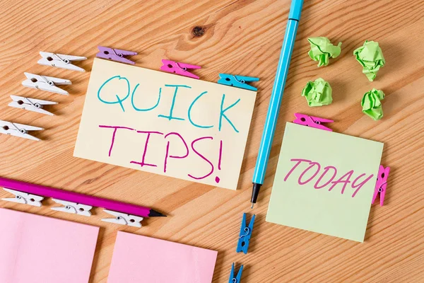 Handwriting text writing Quick Tips. Concept meaning small but particularly useful piece of practical advice Colored clothespin papers empty reminder wooden floor background office.