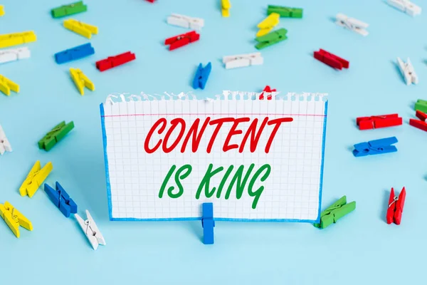 콘텐츠를 보여주는 텍스트 기호는 King입니다. 개념적 사진은 콘텐츠가 웹 사이트의 성공의 중심이라고 생각 컬러 옷핀 종이 빈 알림 블루 플로어 배경 사무실 핀. — 스톡 사진