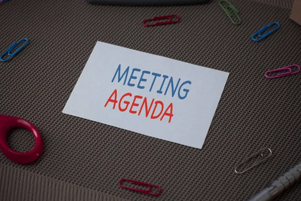 Handschrift Text Schreiben Besprechungsagenda. Konzept, d.h. Dinge, die die Teilnehmer bei einem Meeting zu erreichen hoffen Schere und Schreibgeräte plus einfaches Blatt über strukturiertem Hintergrund. — Stockfoto