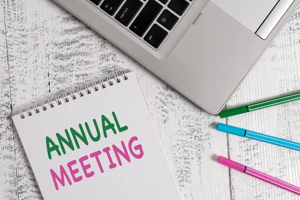 Word writing text Annual Meeting. Business concept for yearly meeting of the general membership of an organization Top trendy metallic laptop blank spiral notepad pens lying wooden table.