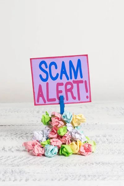 Conceptual hand writing showing Scam Alert. Business photo text fraudulently obtain money from victim by persuading him Reminder pile colored crumpled paper clothespin wooden space.