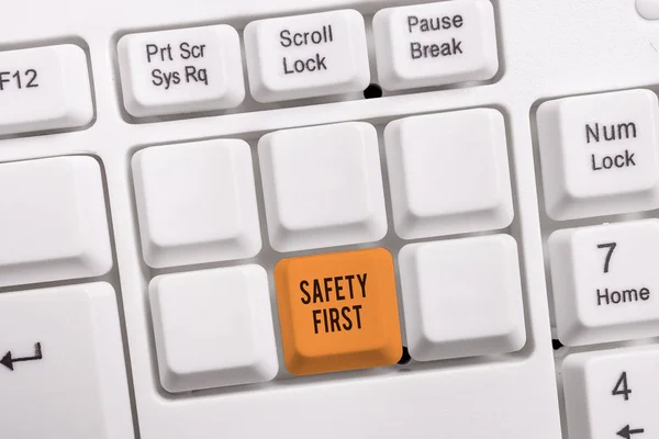 概念手写显示安全第一。商务照片展示过去说，最重要的事情是是安全的白色pc键盘与笔记纸上方的白色背景. — 图库照片
