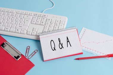 Q Ve A. Business fotoğrafını gösteren ve birinin sorulara cevap verdiği bir zaman dilimini veya bir olayı gösteren not yazma Kağıt mavi klavye ofis çalışması not defteri grafik numaraları notu.