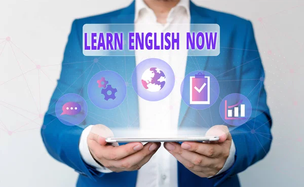 Word writing text Learn English Now. Business concept for gain or acquire knowledge and skill of english language Male human wear formal work suit presenting presentation using smart device.