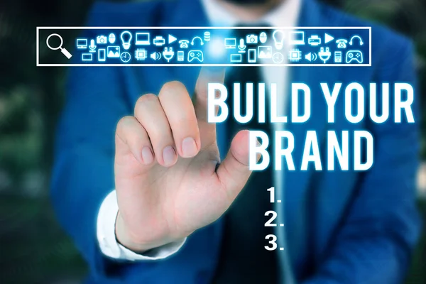 Word writing text Build Your Brand. Business concept for enhancing brand equity using advertising campaigns Male human wear formal work suit presenting presentation using smart device.