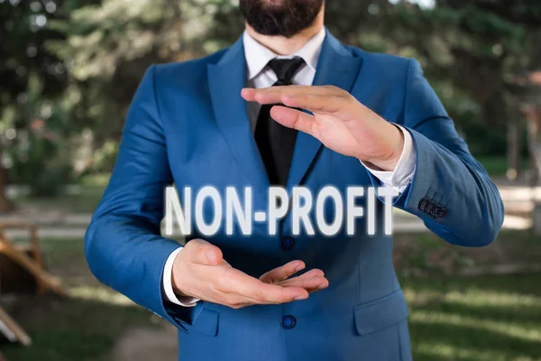 Handwriting text Non Profit. Concept meaning type of organization that does not earn profits for its owners Man with opened hands stands in suite. Concept with copy space and man.