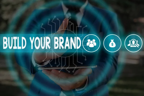 Handwriting text Build Your Brand. Concept meaning enhancing brand equity using advertising campaigns Male human wear formal work suit presenting presentation using smart device.