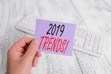 2019 Trendlerini gösteren metin işareti. Kavramsal fotoğraf genel yön hangi bir şey gelişmekte olan veya renkli hatırlatma kare şeklinde kağıt beyaz klavye ahşap zemin tutan adam değişiyor.