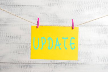 Conceptual hand writing showing UPDATE. Business photo text make something more modern or up to date like software program Clothespin rectangle shaped paper reminder white wood desk.