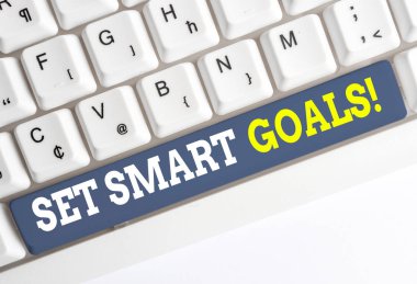 Set Smart Goals'ı gösteren kavramsal el yazısı. Fikirodaklama çabaları nızı netleştirmek için iş fotoğrafı metin listesi beyaz arka plan üzerinde not kağıdı ile akıllıca beyaz pc klavye kullanın.