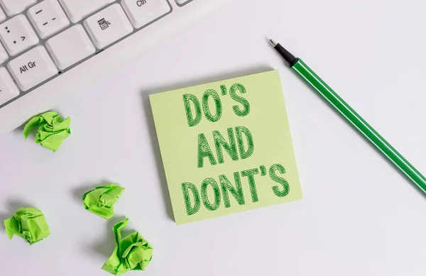 Conceptual hand writing showing Do S Is And Dont S Is. Business photo text advising Rules or customs concerning some activity Green note paper with pencil on white background and pc keyboard. — Stock Photo, Image