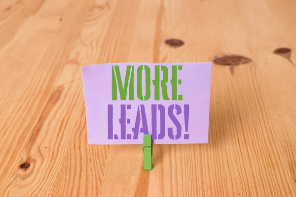 Daha Fazla Müşteri Adayı gösteren not yazma. Ürün veya hizmetler ahşap zemin arka plan yeşil clothespin oluk yuvası ofis içine başlatma tüketici faiz soruşturma vitrine.