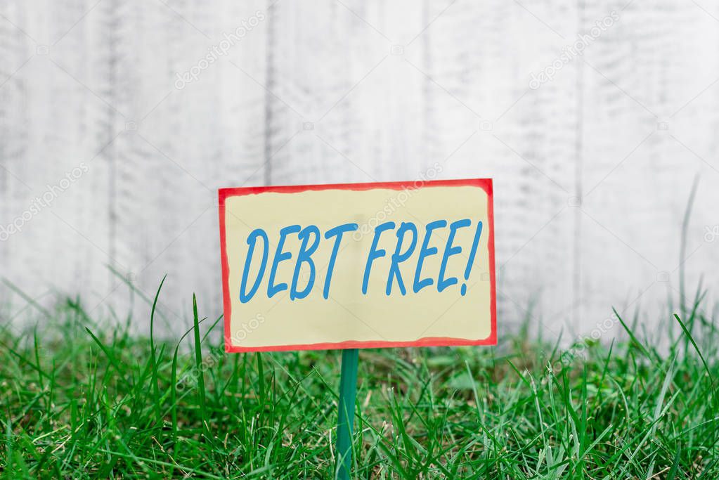 Writing note showing Debt Free. Business photo showcasing does not owning any money or things to any individual or companies Plain paper attached to stick and placed in the grassy land.