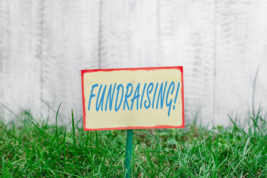 Writing note showing Fundraising. Business photo showcasing seeking to generate financial support for charity or cause Plain paper attached to stick and placed in the grassy land.
