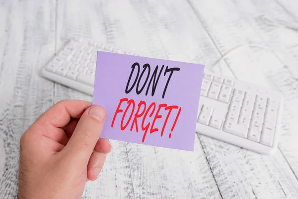 Tekst teken weergeven van Don T vergeten. Conceptuele foto gebruikt om iemand te herinneren over belangrijk feit of detail man Holding kleurrijke herinnering vierkant gevormde papier wit toetsenbord houten vloer. — Stockfoto