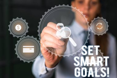 Word writing text Set Smart Goals. Business concept for list to clarify your ideas focus efforts use time wisely Woman wear formal work suit presenting presentation using smart device.