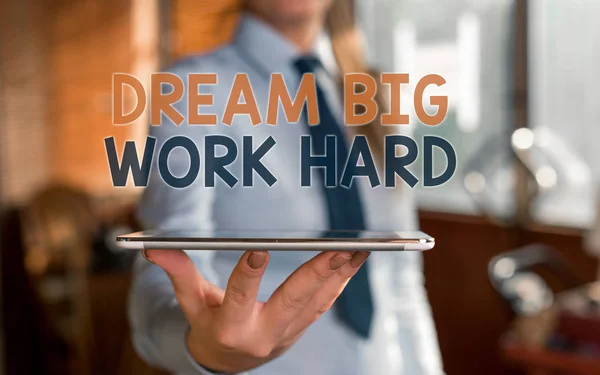 Writing note showing Dream Big Work Hard. Business photo showcasing Believe in yourself and follow the dreams and goals Blurred woman in the background pointing with finger in empty space.