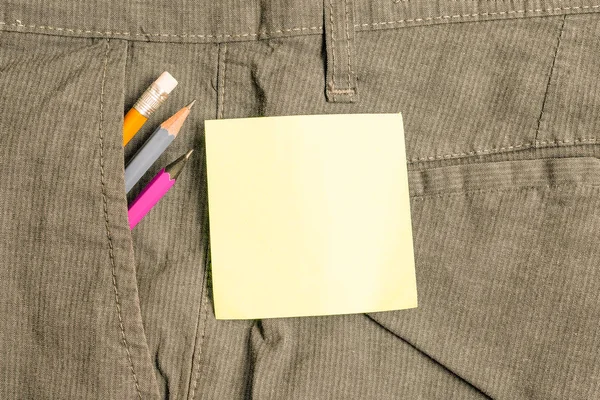 Skriv utrustning och grön anteckningspapper inuti den formella arbets byxan fram ficka. Stationär penna med notationsark placeras i man arbete byxor — Stockfoto