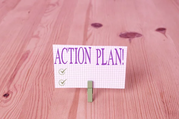 Writing note showing Action Plan. Business photo showcasing proposed strategy or course of actions for certain time Wooden floor background green clothespin groove slot office.