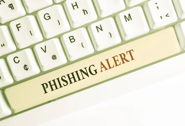 Schreiben Notiz zeigt Phishing-Alarm. Geschäftsfoto, das bewusst betrügerische Versuche zeigt, an sensible Informationen zu gelangen weiße PC-Tastatur mit Notizpapier über weißem Hintergrund. — Stockfoto