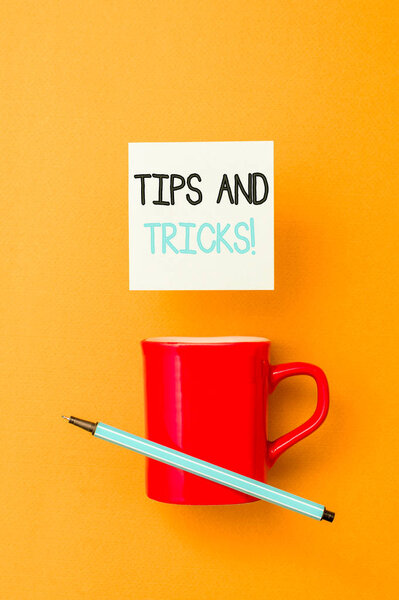 Writing note showing Tips And Tricks. Business photo showcasing means piece advice maybe suggestion how improve Front view coffee cup colored sticky note pen yolk color background.