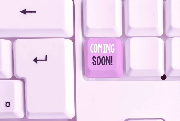 Text sign showing Coming Soon. Conceptual photo event or action that will happen after really short time White pc keyboard with empty note paper above white background key copy space.
