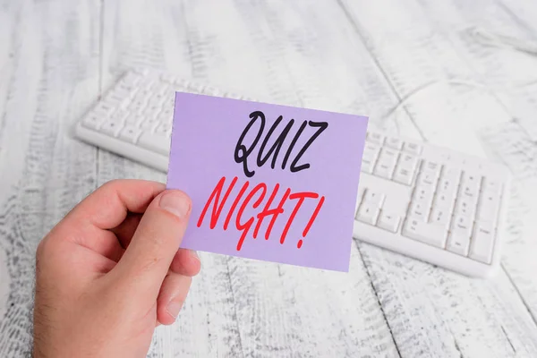 Tekst teken dat Quiz Night weergeeft. Conceptuele foto avond test kennis competitie tussen individuen man Holding kleurrijke herinnering vierkant gevormde papier wit toetsenbord houten vloer. — Stockfoto