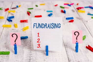 Bağış toplamayı gösteren bir metin işareti. Ahşap masaya yerleştirilen ataçlarla karalama ve parçalanan levhayı belirli bir amaç için para toplama veya üretme kavramsal fotoğraf eylemi.