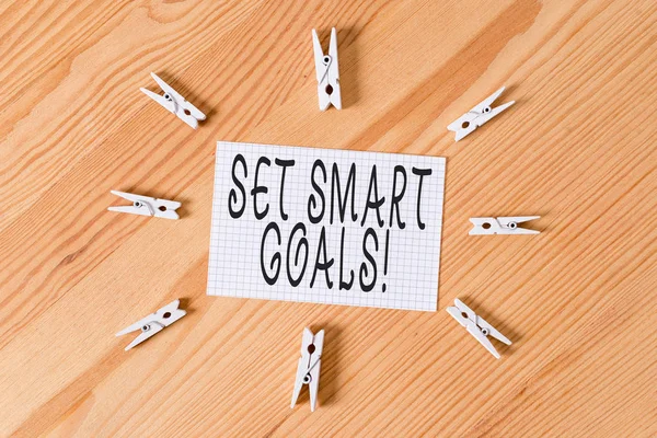 Conceptual hand writing showing Set Smart Goals. Business photo text list to clarify your ideas focus efforts use time wisely Colored crumpled papers wooden floor background clothespin.