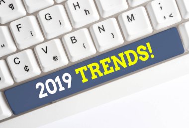 2019 Trendlerini gösteren kavramsal el yazısı. Bir şeyin beyaz arka plan üzerinde not kağıdı yla Beyaz bilgisayar klavyesi geliştirdiği veya değiştirdiği iş fotoğrafı metni genel yönü.