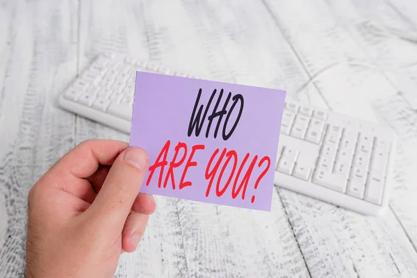 Signo de texto que muestra quién es usted pregunta. Foto conceptual preguntando sobre alguien identidad o demostrando información hombre celebración colorido recordatorio cuadrado en forma de papel teclado blanco piso de madera . — Foto de Stock