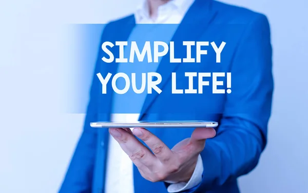 Handwriting text Simplify Your Life. Concept meaning focused on important and let someone else worry about less ones Man in the blue suite and white shirt holds mobile phone in the hand.