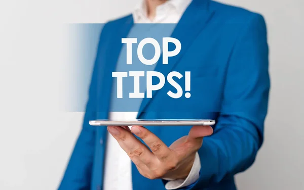 Handwriting text Top Tips. Concept meaning small but particularly useful piece of practical advice Man in the blue suite and white shirt holds mobile phone in the hand.