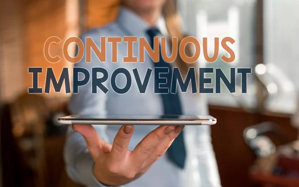 Writing note showing Continuous Improvement. Business photo showcasing ongoing effort to improve products or processes Blurred woman in the background pointing with finger in empty space.
